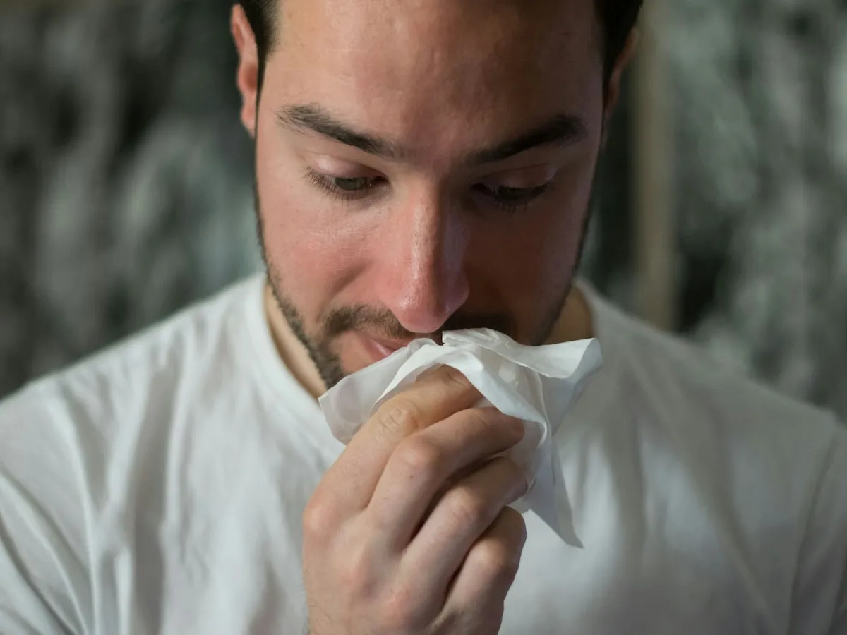 A man blowing his nose into a tissue
