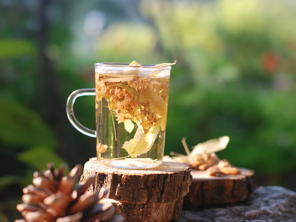 A glass of herbal tea on a wooden stump outdoors