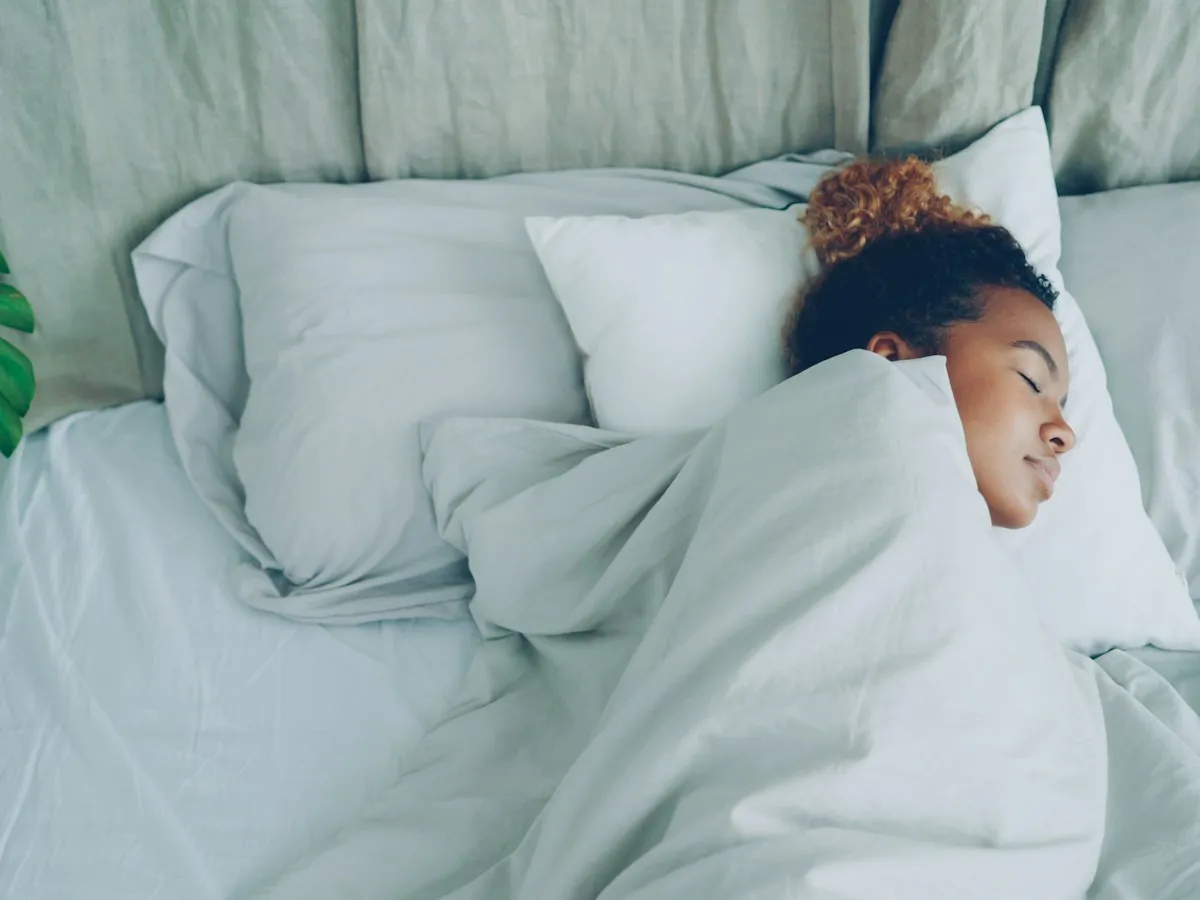 A woman sleeping peacefully in a white bed